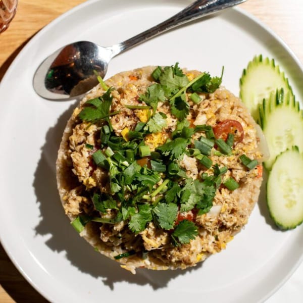 Kin Dee Thai's crab fried rice with cilantro, scallions, and cucumber slices on a white plate.