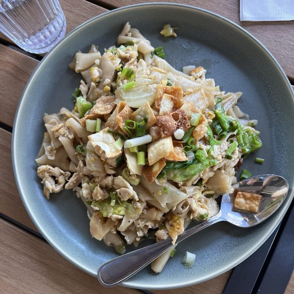 Kin Dee Thai's Pad See Ew with wide noodles, chicken, egg, and green onions on a grey plate.