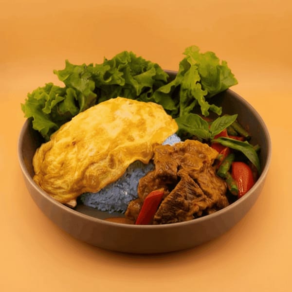 Kin Dee Thai's blue rice with beef curry, omelet, lettuce, and vegetables in a bowl.